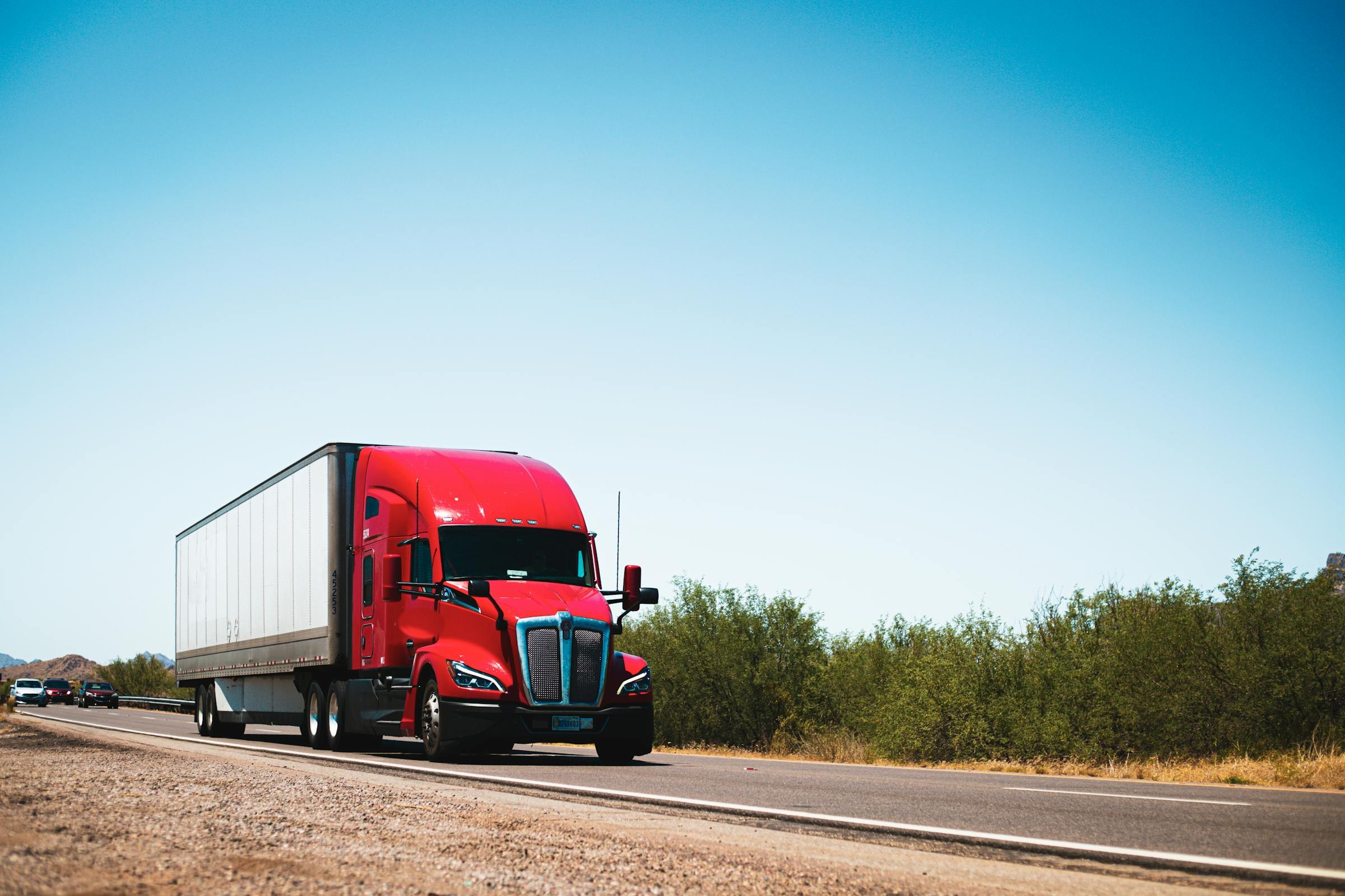 Red Kenworth T680 tractor-trailer traveling on a sunny U.S. highway